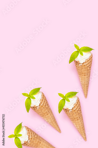 Lots of vanilla ice cream in a waffle cone on a pink background