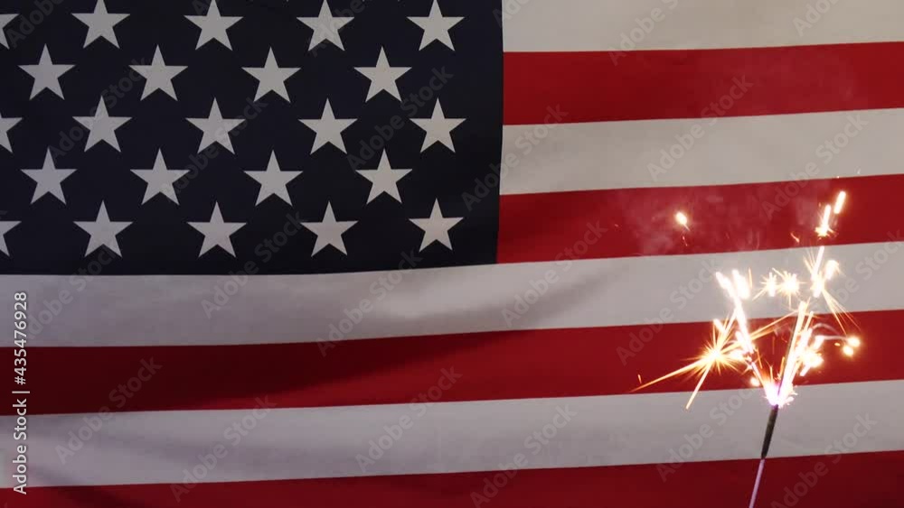A sparkler candle on the background of the American flag. A day of