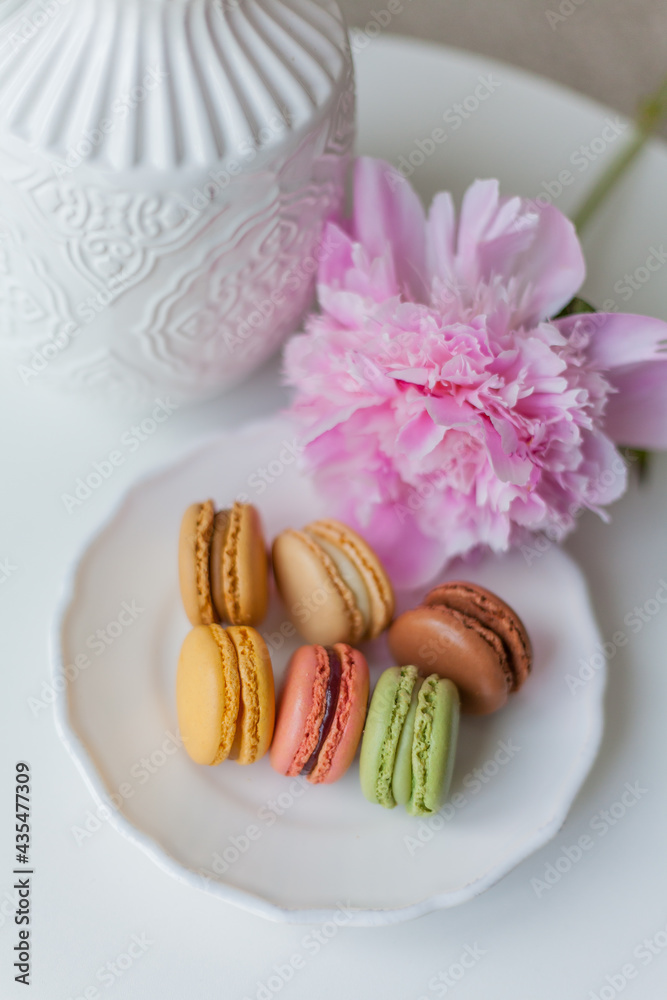 Living room interior. Bouquet of pink peonies in a vase, multicolored French macaroon pastries. Cozy. Spring. Living room interior. Bouquet of pink peonies in a vase, multicolored French macaroon pastries. Cozy. Spring.