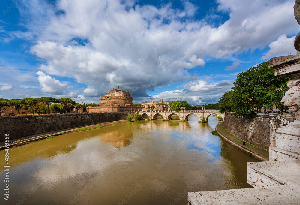 View of River Tiber with the Holy Angel Castle and Bridge under a cloudy sky in Rome, from the nearby Victor Emmanuel II Bridge