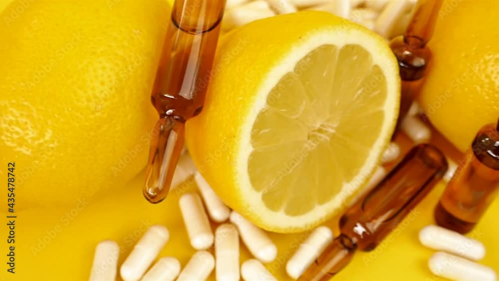 Vitamin C tablets and ampoules. Strengthening immunity and health. glass ampoules, vitamin C capsules and cut lemons on a yellow background. Medicine and health concept