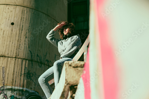 Portrait of a girl with curly hair dressed casually standing outdoors and looking away.