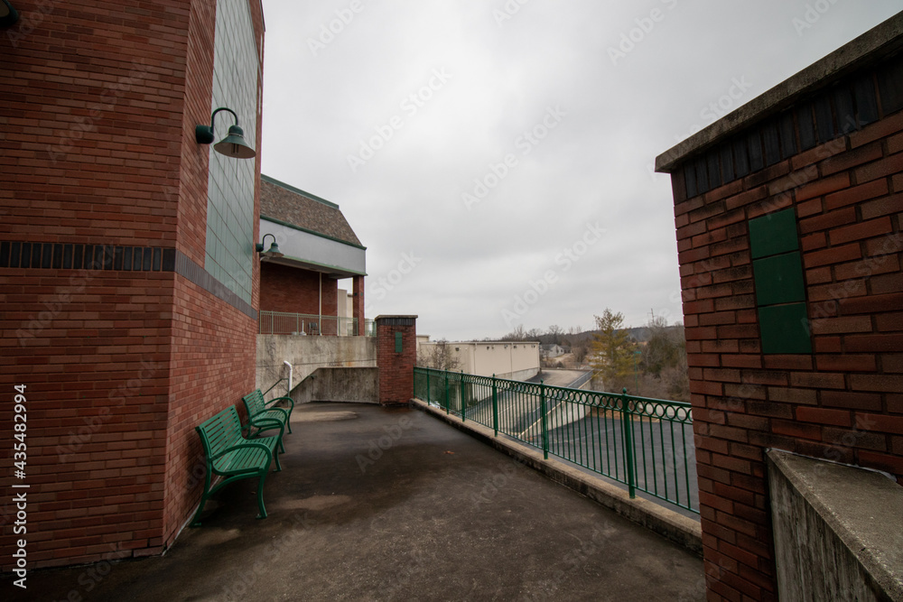 Back of brick building shopping center on cloudy day in winter with green metal park benches, super wide angle lens shot