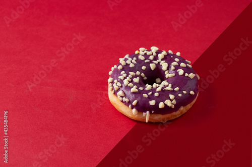 Blueberry glaze donut with nuts  topping on two colour background photo