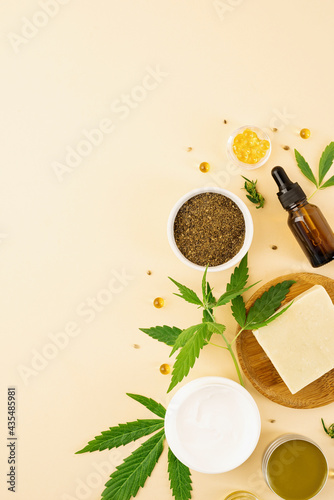 cbd oil and cannabis leaves cosmetics top view on orange background
