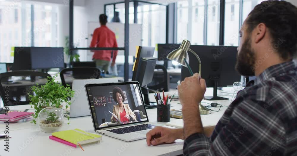 Mixed race businessman sitting at desk using laptop having video call with female colleague Mixed race businessman sitting at desk using laptop having video call with female colleague