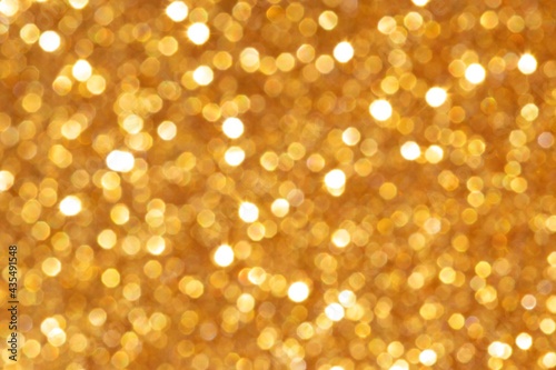 Golden sequin bokeh with a bright glow. Festive mood. Blurred background.
