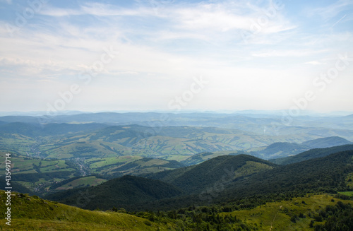 Grassy mountain tops with forests on slopes, cozy villages in the valley, Carpathian Mountains, Ukraine