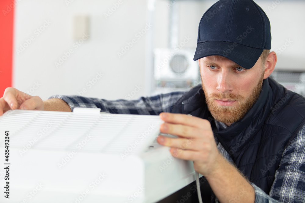 young male technician is repairing a printer at office young male technician is repairing a printer at office