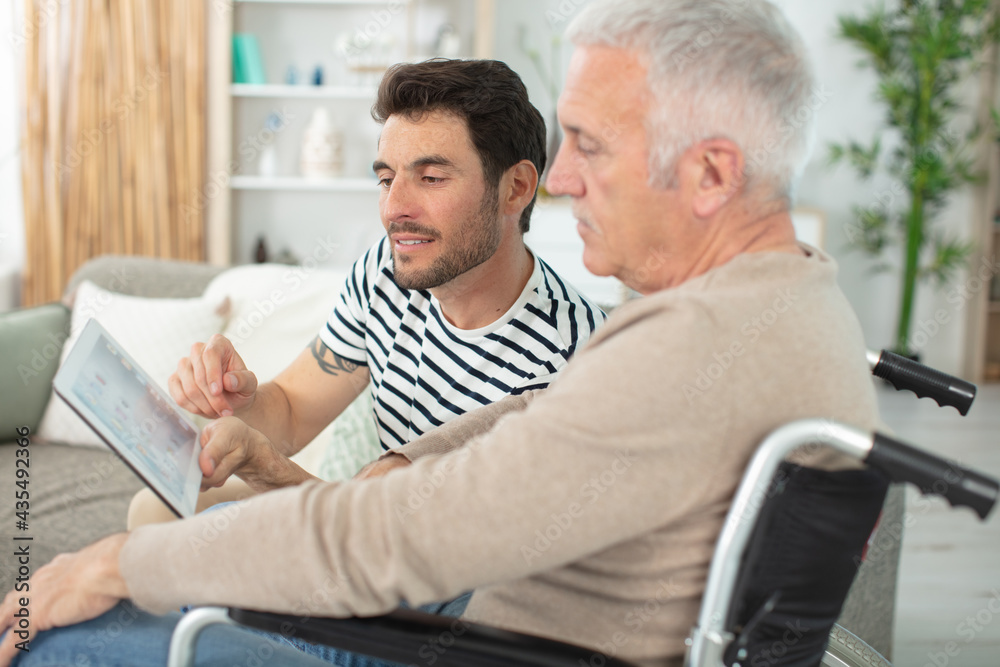 handsome son with disabled father in wheelchair at home handsome son with disabled father in wheelchair at home