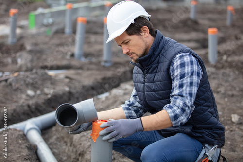 plumber fixing sewerage pipe at construction site photo