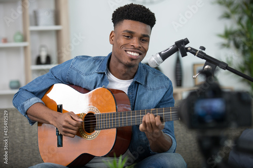 man recording a guitar and singing performance on camera