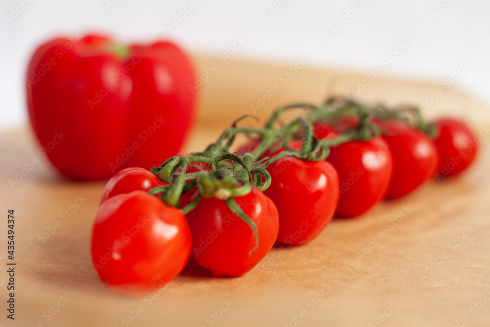 red cherry tomatoes, red bell pepper on a parchment paper , white background red cherry tomatoes, red bell pepper on a parchment paper , white background