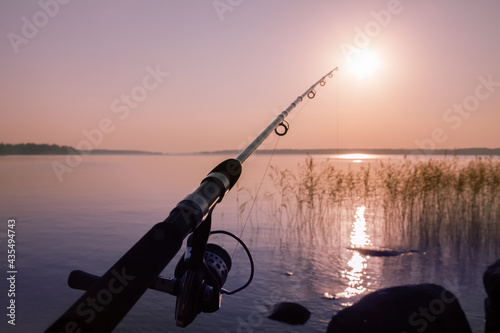 fishing rod against the backdrop of a deserted calm pink sunset