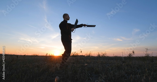 Silhouette of young male kung fu fighter practising alone in the fields during sunset	