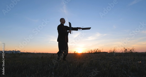 Silhouette of young male kung fu fighter practising alone in the fields during sunset 