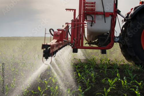 Tractor spraying pesticides at corn fields photo