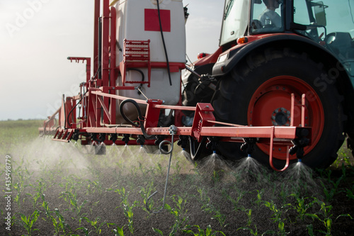 Tractor spraying pesticides at corn fields