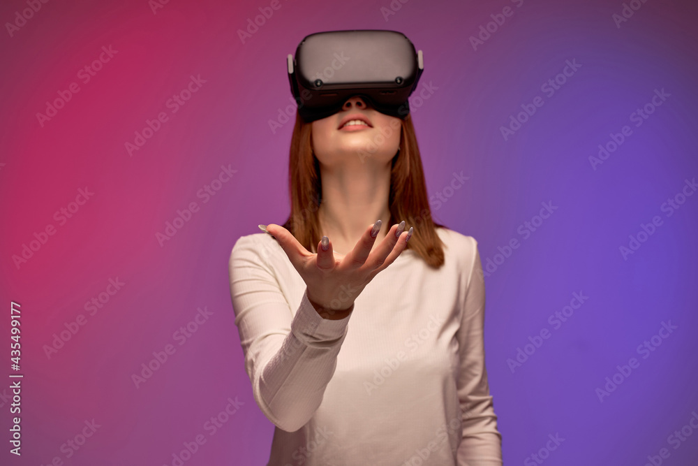 excited young female in virtual reality helmet, looking into VR glasses screen. Young caucasian woman is surprised by reality VR helmet, holds out hand forward. portrait. modern technologies concept excited young female in virtual reality helmet, looking into VR glasses screen. Young caucasian woman is surprised by reality VR helmet, holds out hand forward. portrait. modern technologies concept