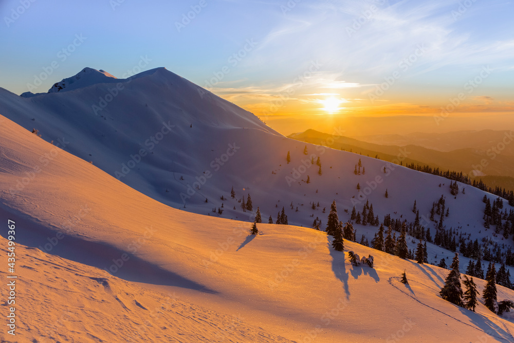 Sunset in the winter mountains, orange sky in the snowy Carpathians
