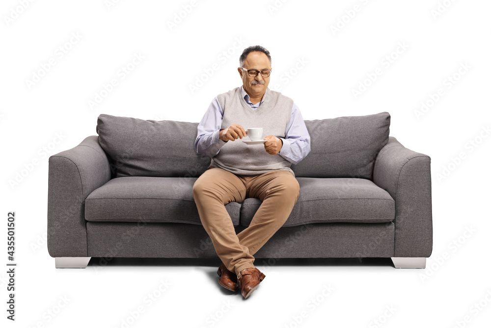 Mature man sitting on a sofa and drinking a cup of coffee