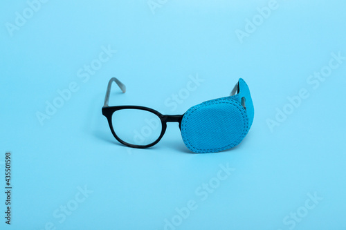 Children's glasses with occluder on a colored background. Lazy eye. Amblyopia