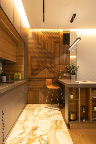 Stylish modern kitchen interior, details, studio. High bar stool, designer wood veneer panel on wall. Concept minimal, fashionable interior, natural materials, wood, marble, metal. Vertical.