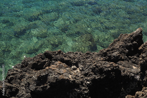 Brzeg morza, ciemne kamienie i przezroczysta woda, Kreta, Grecja