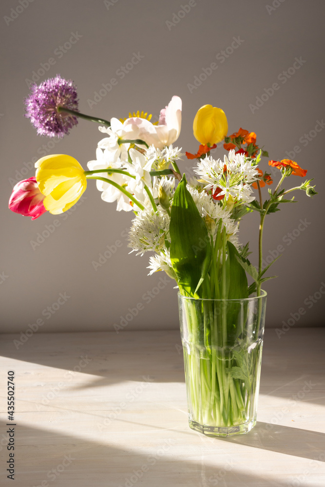 bouquet of colorful bright garden flowers in vase in sun light on white table