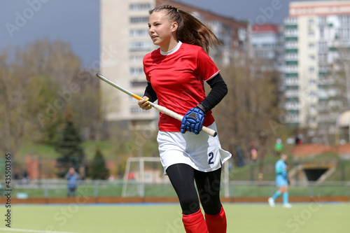 Young field hockey girl player runs with the stick