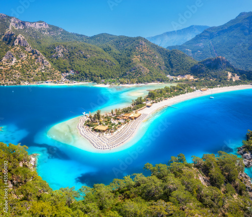 Fototapeta Naklejka Na Ścianę i Meble -  Aerial view of sea bay, sandy beach with umbrellas, trees, mountain at sunny day in summer. Blue lagoon in Oludeniz, Turkey. Tropical landscape with island, white sandy bank, blue water. Top view