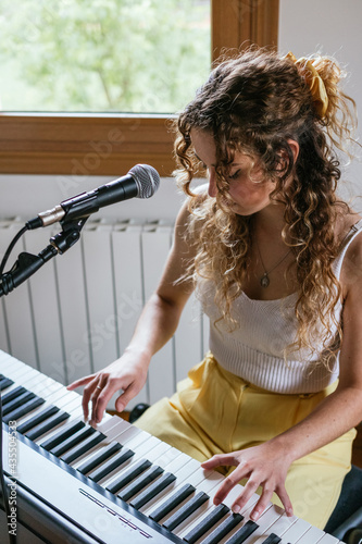 Young woman playing piano at home studio