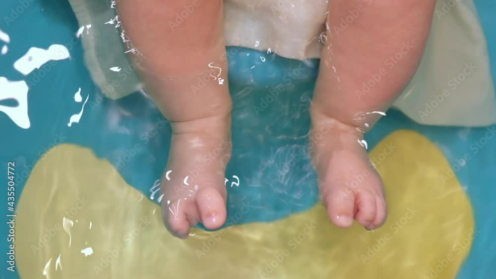 Little Child taking a bath at home. Baby's feet in the water. One