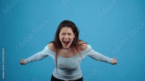 The angry young woman, overloaded with the problem, strives with all her might to feel better. Asian with dark hair, dressed in a blue blouse, isolated on a dark blue background in the studio. The photo