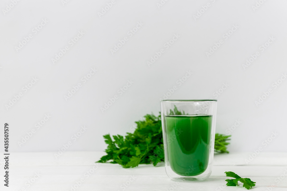 Glass cup with healthy drink of liquid chlorophyll on white background with green leaves. Image with copy space Glass cup with healthy drink of liquid chlorophyll on white background with green leaves. Image with copy space
