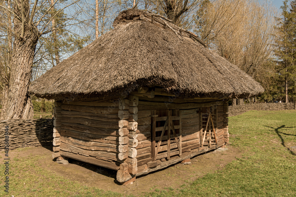An old rural thatched-roofed farmhouse built of logs. An old rural thatched-roofed farmhouse built of logs.