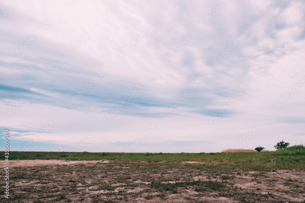 View on a plain with rare grass against the backdrop of a cloudy sky. View on a plain with rare grass against the backdrop of a cloudy sky.