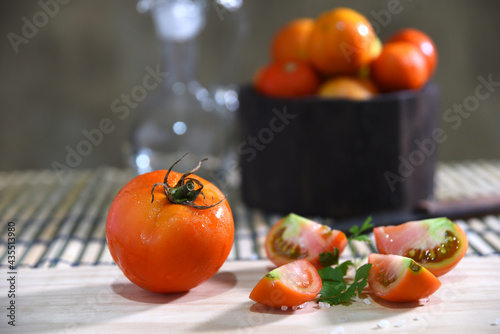 tomatoes cut into slices on the table on blurred background with space for text