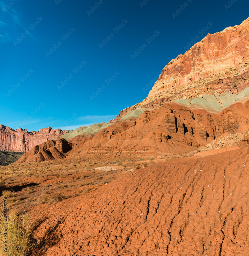 Red Hills of Eroded Sand and Clay Below the Steep Cliffs of the Waterpocket Fold, Capitol Reef National Park, Utah, USA