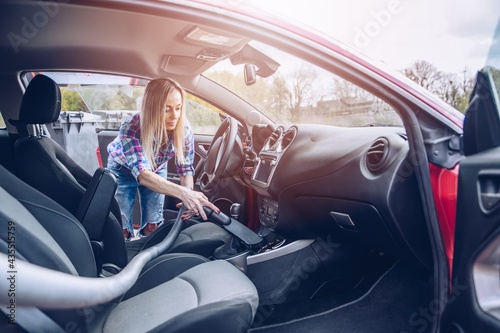 Obraz na płótnie Blonde woman removs dust with a vacuum cleaner during car cleaning. w salonie
