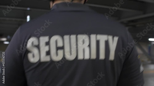 A shallow focus of security personnel walking and observing along a building's premises in 4K photo