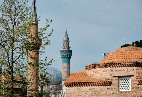 Nicaea (iznik), Bursa Turkey.  seyh  kutbuddin and its son tomb made of red bricks wall with its minaret extends to blue cloudy sky with green mosque (yesil cami) minaret background behind tree.