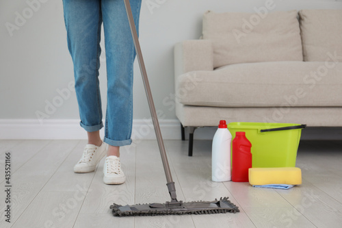 Woman washing floor with mop in living room  closeup