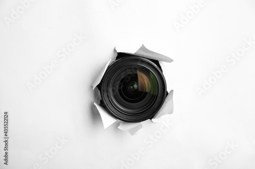 Hidden camera lens through torn hole in white paper