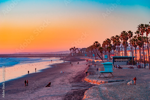 Fotografia A Oceanside sunset at the beach draws people to it to walk and relax and the ocean shoreline
