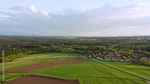 Wonderful spring day, flying forward smooth over a green field with a little village and a forest. photo