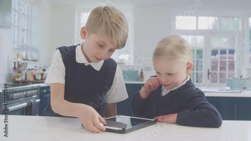 Wallpaper Mural Two children wearing school uniform in kitchen playing with digital tablet on counter - shot in slow motion Torontodigital.ca