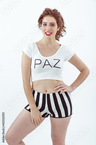 Chica sexy posa con una remera blanca ajustada y un short con rayas negras photo