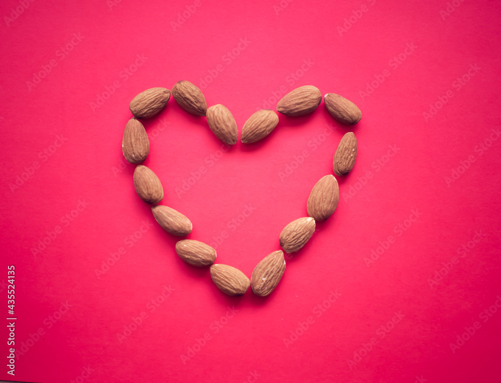 Obraz premium Heart shaped almonds on a soft pink background, heart health, Valentine's Day 