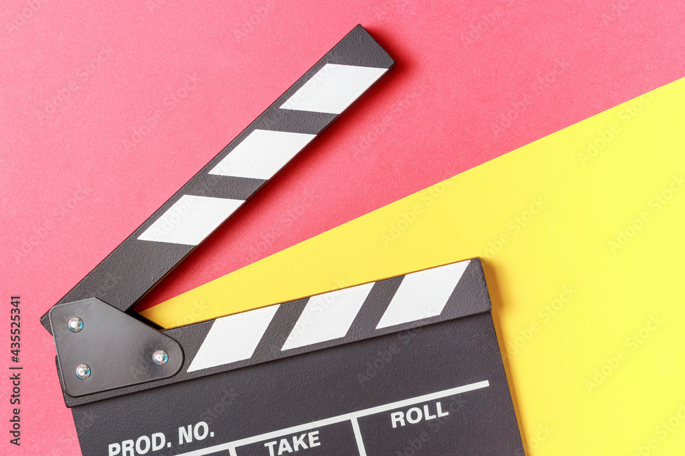 The clapperboard on yellow and red background close-up top view.